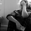 Jeune fille triste, assise par terre, son téléphone à la main