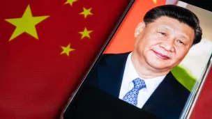 Photographie de Xi Jinping devant le drapeau de la République populaire de Chine.