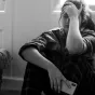 Jeune fille triste, assise par terre, son téléphone à la main