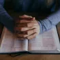 Les mains jointes d'un homme méditant la Parole de Dieu